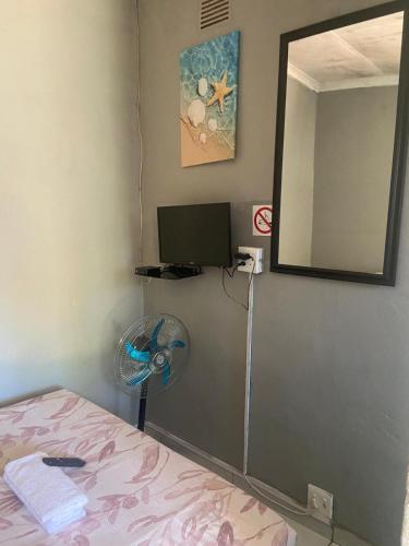 a bedroom with a fan and a mirror and a bed at Bennyz Guest House in Pretoria