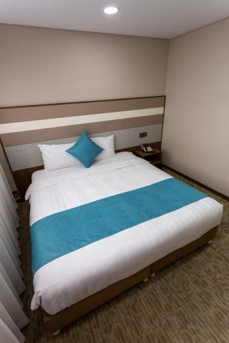 a bedroom with a large bed with blue pillows at The Recenz Dongdaemun Hotel in Seoul