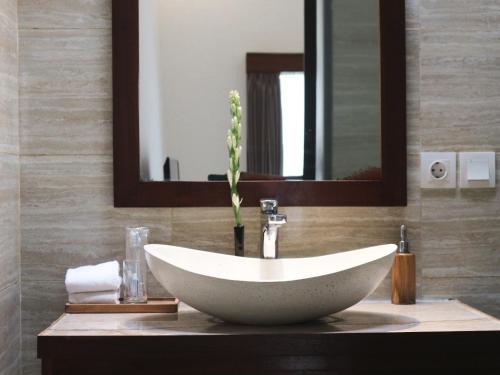 a bathroom with a white sink and a mirror at Villa Sinergi 2BR Tranquil Villa in Seminyak in Seminyak