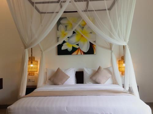 a bedroom with a white bed with flowers on the wall at Villa Sinergi 2BR Tranquil Villa in Seminyak in Seminyak