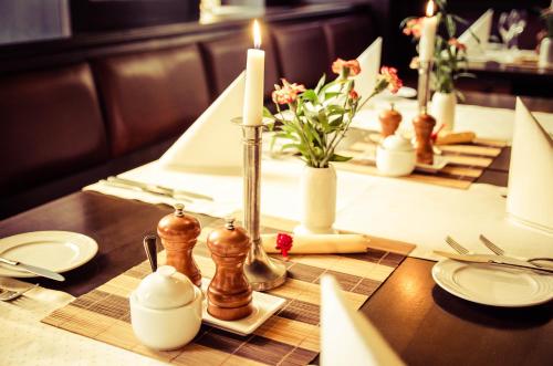a table with candles and plates and flowers on it at Hotel Wilder Mann Annaberg-Buchholz in Annaberg-Buchholz