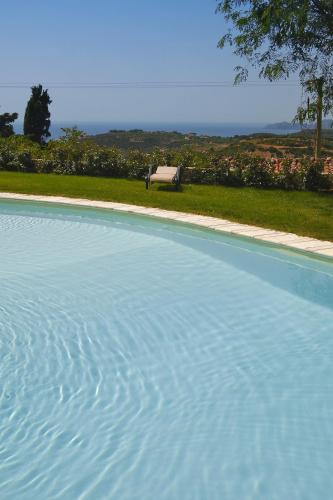 a large blue swimming pool with a bench in the background at Hotel Villa Gli Asfodeli in Tresnuraghes