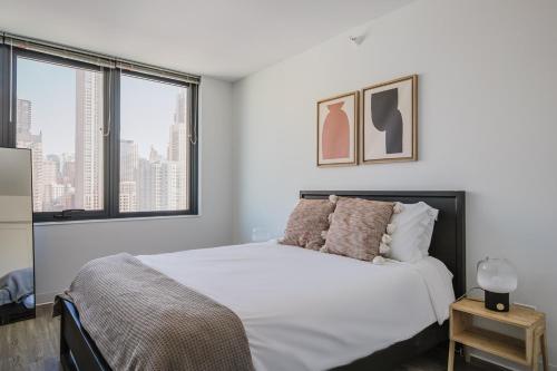 a bedroom with a bed with white sheets and windows at Blueground River North pool AC nr park CHI-1193 in Chicago