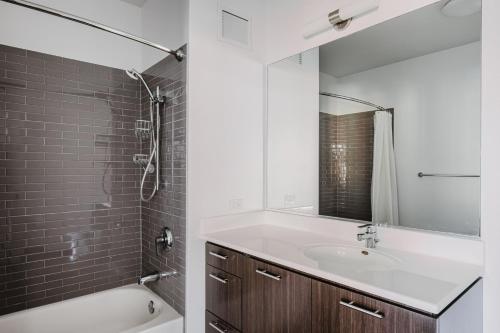 a bathroom with a sink and a tub and a mirror at Blueground River North pool AC nr park CHI-1193 in Chicago