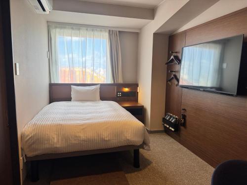 a bedroom with a bed and a flat screen tv at Hotel Palm Royal Resort Kokusai Street in Naha