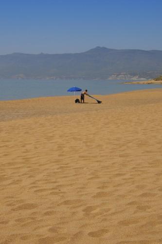 a person sitting under an umbrella on a beach at Hotel Villa Gli Asfodeli in Tresnuraghes