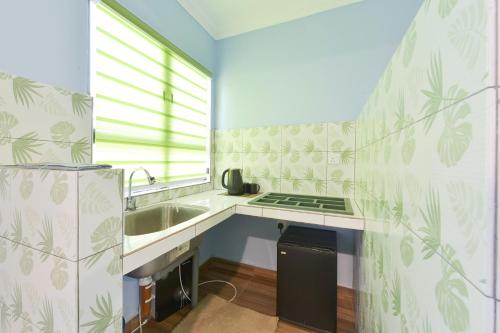 a small kitchen with a sink and a stove at Mersing Pelangi Beach Resort in Mersing