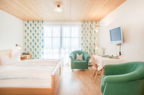 a bedroom with a bed and a chair and a desk at Hotel Dreiländerblick Dornbirn in Dornbirn