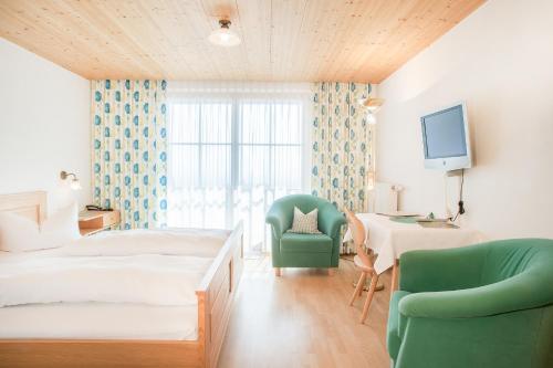 ein Schlafzimmer mit einem Bett, einem Stuhl und einem Schreibtisch in der Unterkunft Hotel Dreiländerblick Dornbirn in Dornbirn