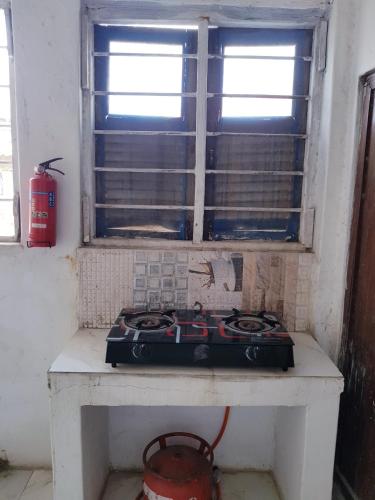 a stove sitting on a table under a window at Balcony Bliss & Private Bath at Mamdalis in Ngambo