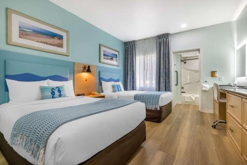 a hotel room with two beds and a bathroom at Quality Suites Downtown San Luis Obispo in San Luis Obispo