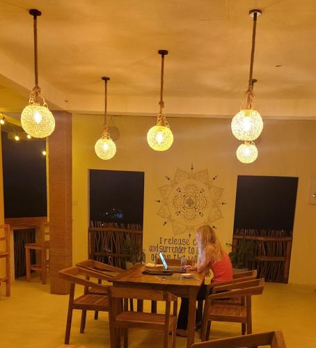 a woman sitting at a table using a laptop at Wake N Flow, Weligama in Weligama