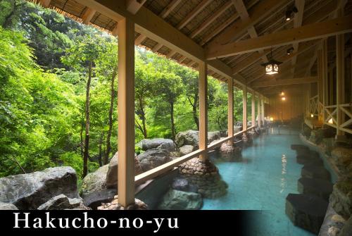 a building with a walkway in the woods at Yamanaka Onsen Kagari Kisshotei in Kaga