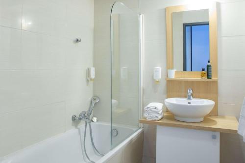 a bathroom with a shower and a sink and a tub at Comfort Aparthotel Frejus La Tour de Mare in Fréjus