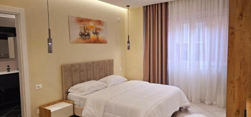 a bedroom with a white bed and a window at Sunset Harmony Apartment in Shkodër