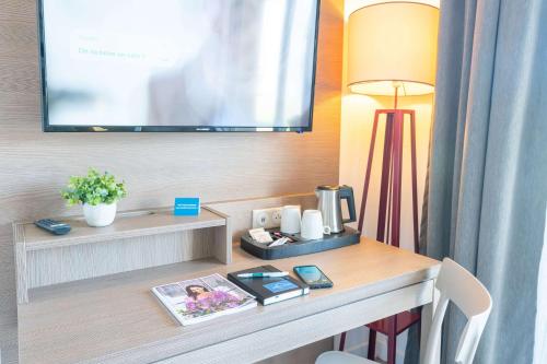 a room with a desk with a tv and a lamp at Comfort Aparthotel Cannes Mandelieu in Mandelieu-la-Napoule