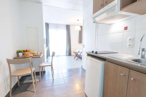 a kitchen with a sink and a table with chairs at Comfort Aparthotel Cannes Mandelieu in Mandelieu-la-Napoule