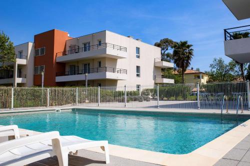 a swimming pool in front of a building at Comfort Aparthotel Cannes Mandelieu in Mandelieu-la-Napoule
