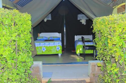 a tent with two beds and a chair in it at Rhino Tourist Camp in Ololaimutiek