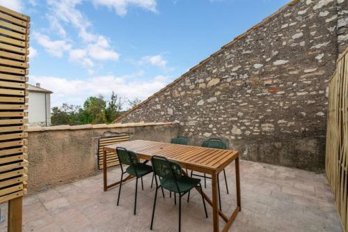 a wooden table and chairs on a patio at L'Euphorbe Terrasse Wifi in Peyriac-de-Mer