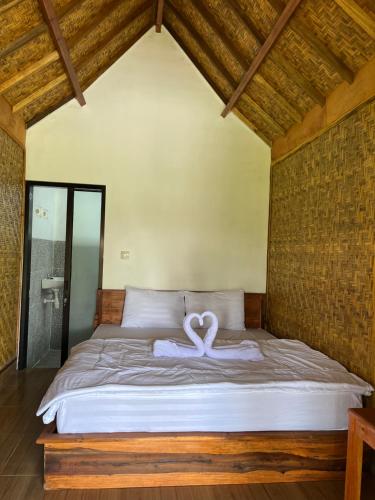 a bed with a heart shaped towel on it at PANORAMA BUNGALOWs in Tetebatu