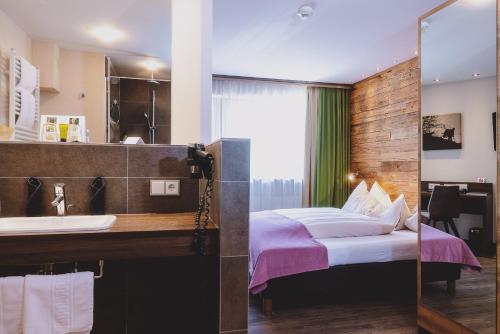 a bathroom with a bed and a sink in a room at Hotel DIE SONNE in Saalbach Hinterglemm