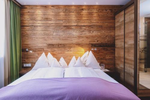 a bedroom with a large bed with a wooden wall at Hotel DIE SONNE in Saalbach Hinterglemm