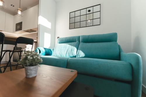 a blue couch in a living room with a table at Macarena Suites in Cáceres
