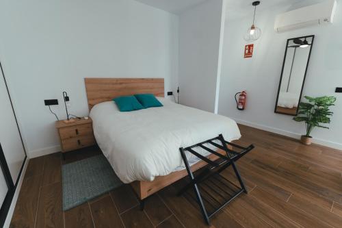 a bedroom with a bed with a chair and a mirror at Macarena Suites in Cáceres