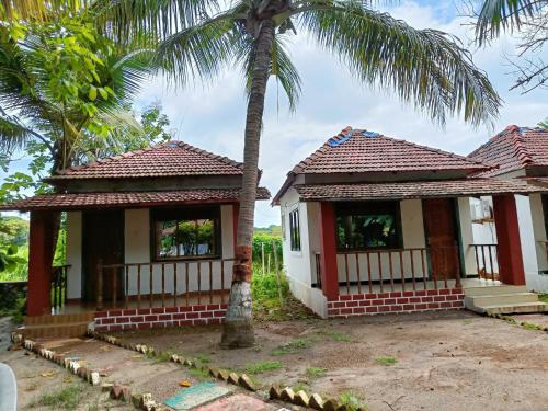 a small house with a palm tree in front of it at Neel Garden Home Stays in Adi