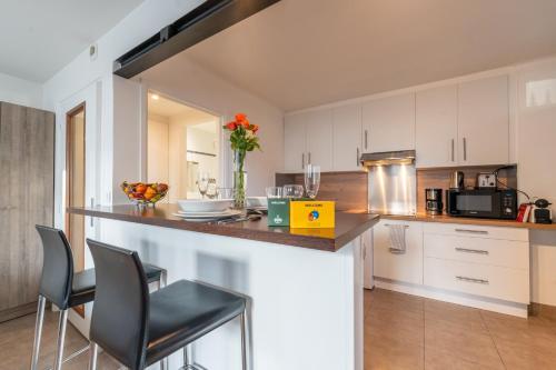 une cuisine avec des placards blancs et un comptoir avec des chaises dans l'établissement Les Coteaux 3 - Studio à 10min de Paris, à Argenteuil