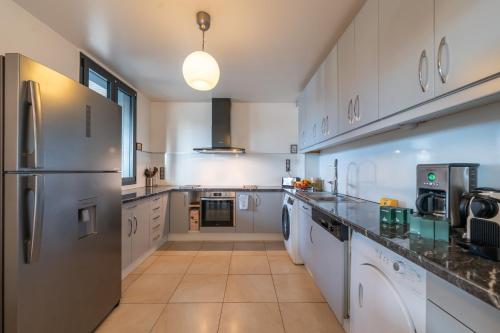 Il comprend une grande cuisine avec des placards blancs et un réfrigérateur. dans l'établissement Les Coteaux 2 - 5 chambres proche CDG, à Argenteuil