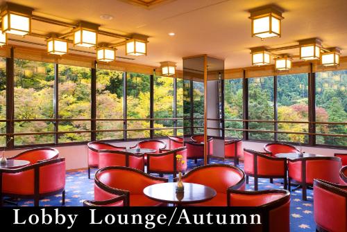 a restaurant with red chairs and large windows at Yamanaka Onsen Kagari Kisshotei in Kaga