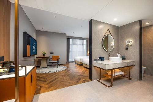 青岛Golden Tulip Qingdao Hongdao Exhibition Center Hotel的客房内的浴室设有床和水槽