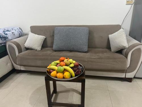 uma taça de fruta numa mesa em frente a um sofá em Smile Apartment Sharjah -FAMILY ONLY em Sharjah