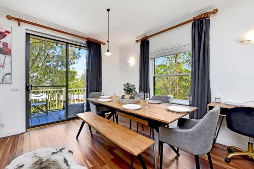 a dining room with a table and chairs and windows at Villa 2br Dolcetto Villa located within Cypress Lakes Resort in Pokolbin