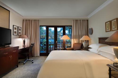 Una habitación de hotel con una cama, un escritorio y un televisor. en AKAR Hotels & Resort Lampung, en Bandar Lampung