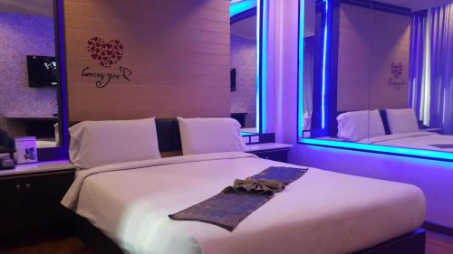 a bedroom with a large white bed with a mirror at Theringkhokmao in Ban Tha Sae