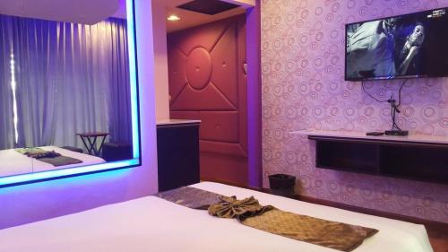 a purple room with a bed and a tv on the wall at Theringkhokmao in Ban Tha Sae
