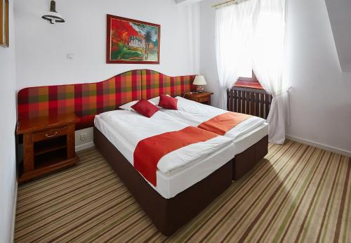 a bedroom with a bed with a red and white blanket at Hotel Pałac w Myślęcinku in Bydgoszcz