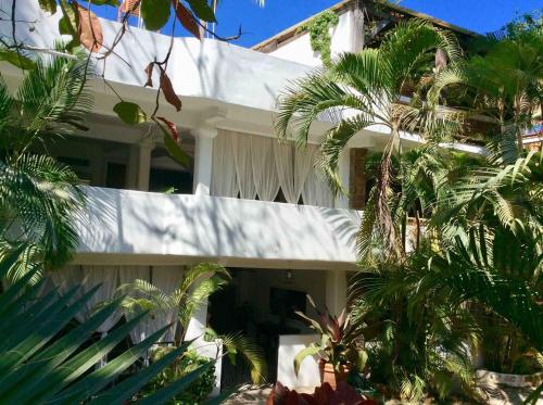 a white house with palm trees in front of it at Casa Mara Beachfront -Heated Pool in Sayulita