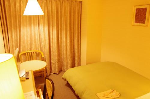 a hotel room with a bed and a table and a window at Hotel Sunroute Goshogawara in Goshogawara