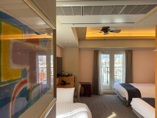 a hotel room with two beds and a ceiling fan at Hotel Palm Royal Resort Kokusai Street in Naha