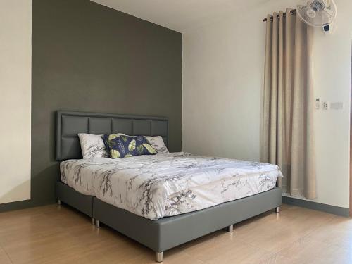 a bed in a bedroom with a gray wall at แม่พริกธารา แม่สรวย in Ban Mae Phrik (1)