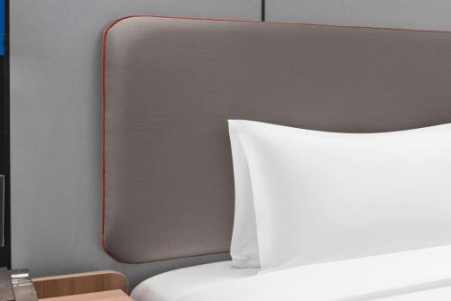 a bed with a white pillow and a mirror at Holiday Inn Express Harbin Central Avenue by IHG in Harbin