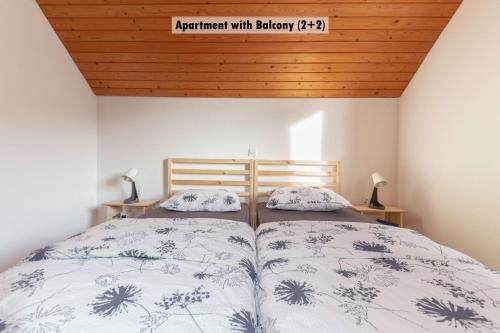 two beds in a bedroom with a wooden ceiling at Apartments Farm House Uric in Jesenice