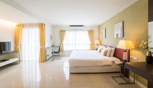 a bedroom with a bed and a desk and a television at Beyond Suite in Bangkok