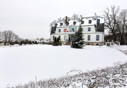 a large white house on a snow covered field at Hotel Pałac w Myślęcinku in Bydgoszcz