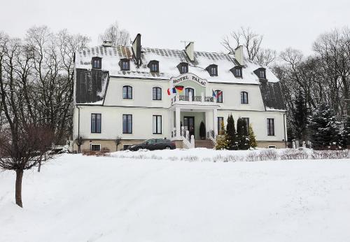 a large white house with snow on the ground at Hotel Pałac w Myślęcinku in Bydgoszcz