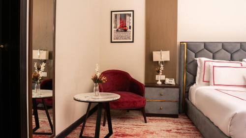 a bedroom with a bed and a red chair and a table at Ramada Resort by Wyndham Gilgit in Gilgit